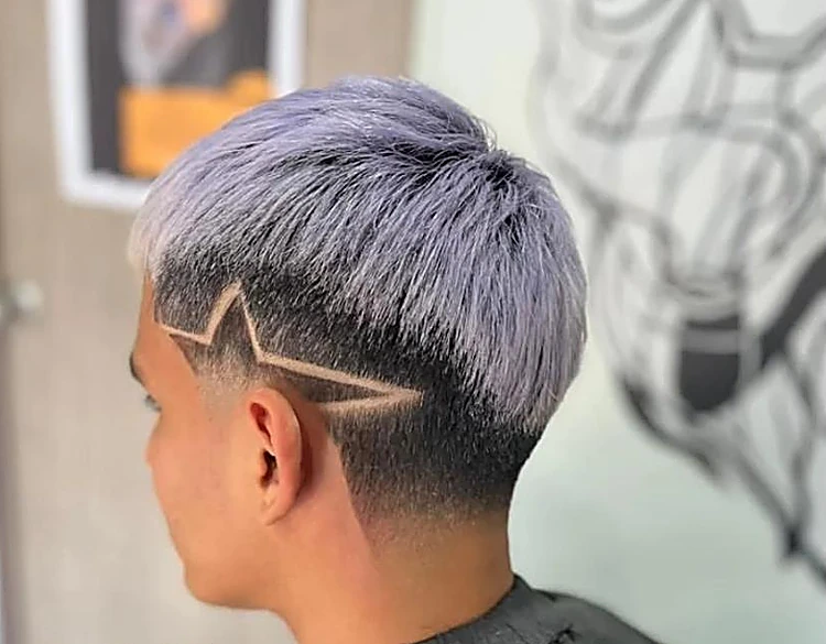 Corte platinado en tono lila con una estrella hecha a navaja en el costado