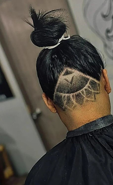 Mandala sombreado a navaja en la nuca, con el cabello largo recogido en chongo
